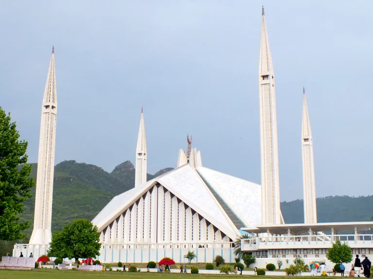 Faisal Mosque in Islamabad with its white minarets and the green Margalla Hills behind
